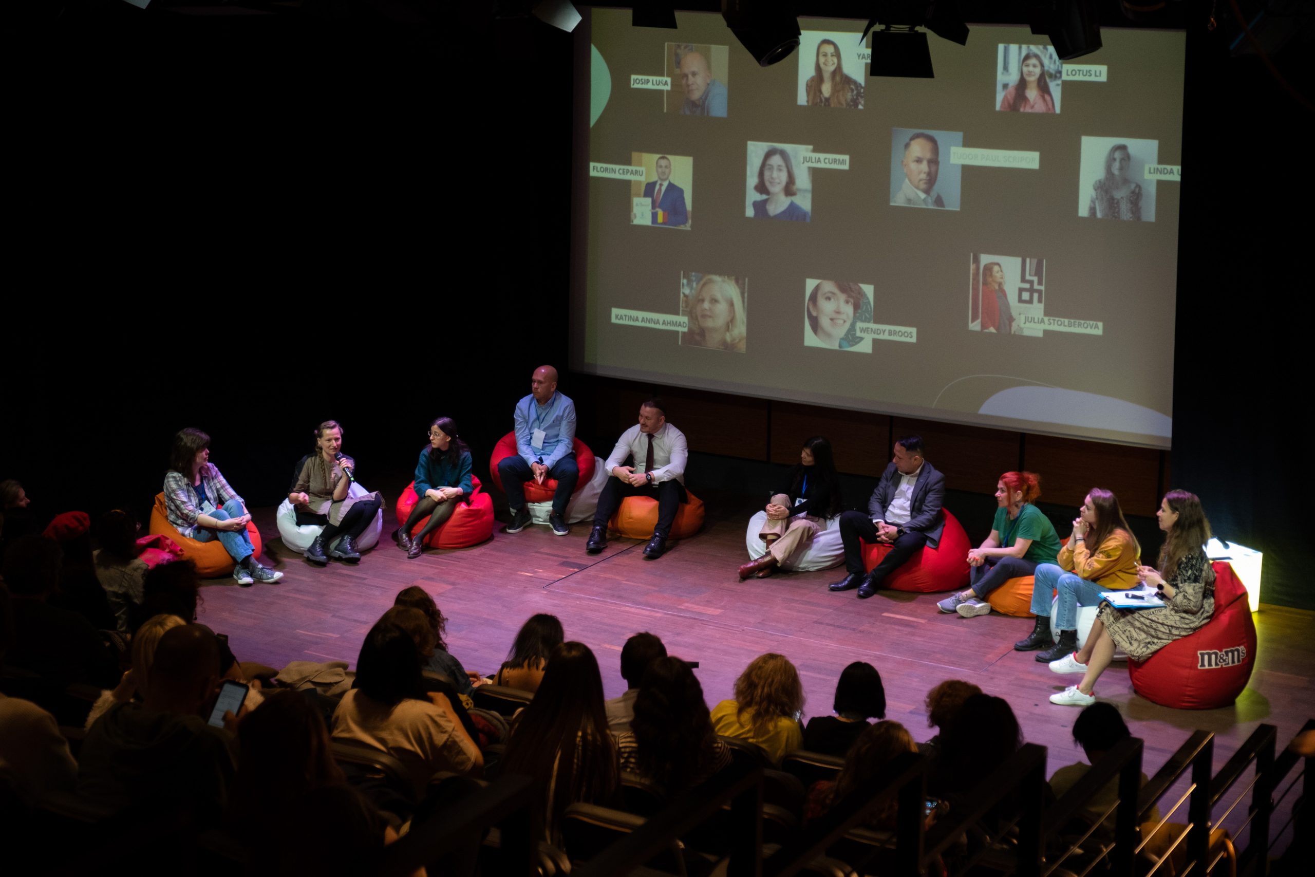 Speakers sitting on a stage in front of audience.