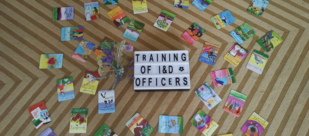 A photo of colorful cards and a sign that says "Training of I&D Officers"