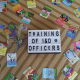 A photo of colorful cards and a sign that says "Training of I&D Officers"
