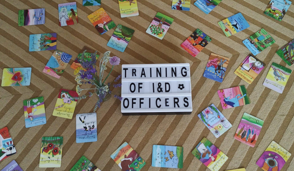 A photo of colorful cards and a sign that says "Training of I&D Officers"