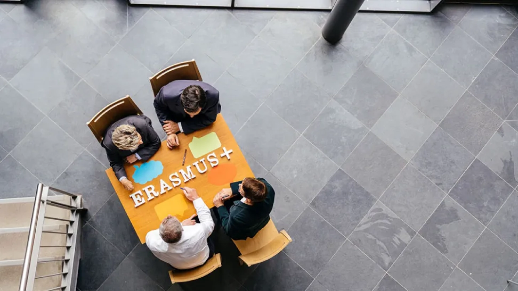 Four people sitting at a desk with the inscription Erasmus+ on top of it. © DAAD/Oliver Reetz