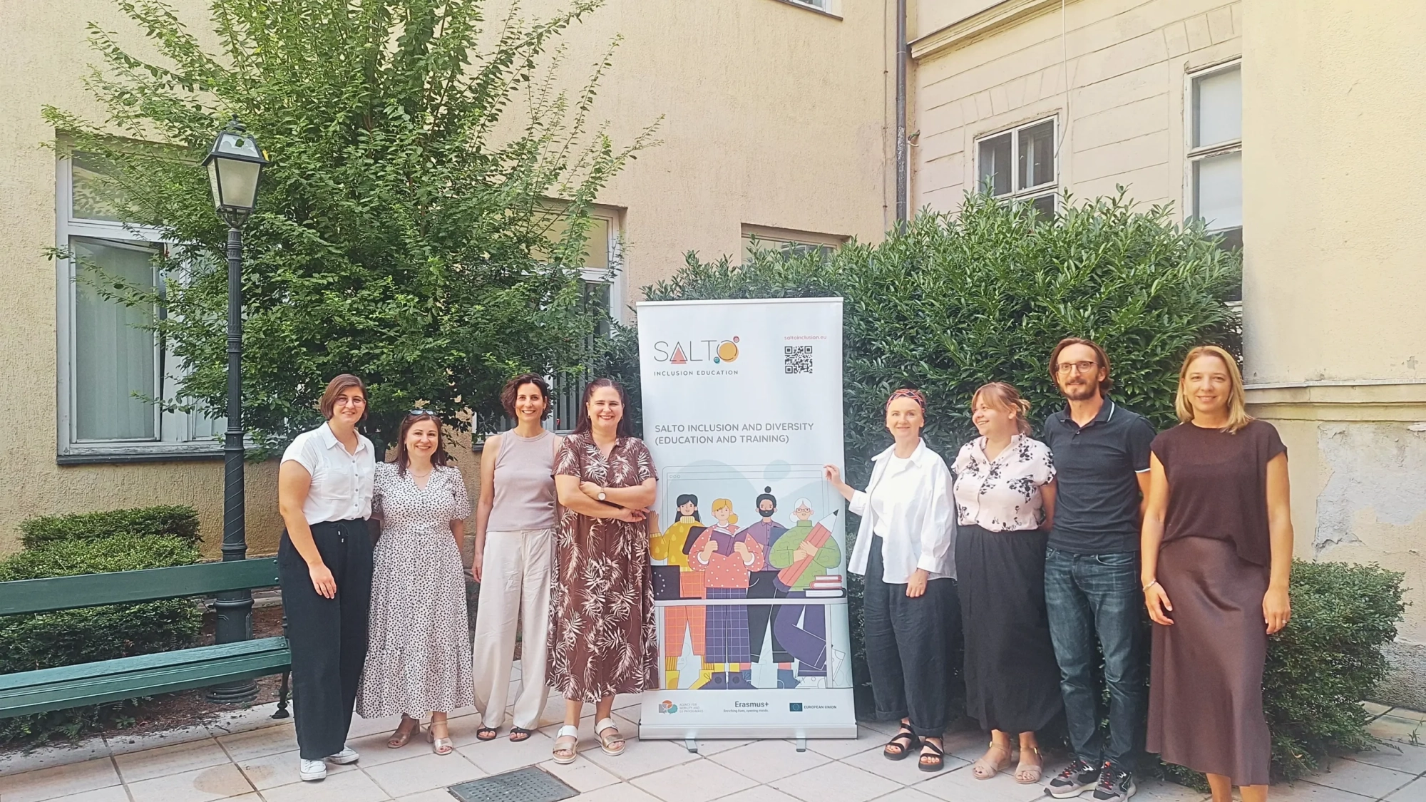 Staff from SALTO ID ET, the Croatian Agency for Mobility and EU Programmes, and the Czech National Agency for International Education and Research pose together outdoors beside a SALTO Inclusion and Diversity banner during a job shadowing visit.